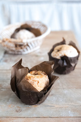 Freshly baked cupcakes muffins on a large textured wooden table. Home-made pastries in parchment paper close-up