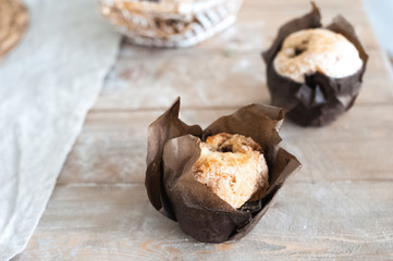 Freshly baked cupcakes muffins on a large textured wooden table. Home-made pastries in parchment paper close-up