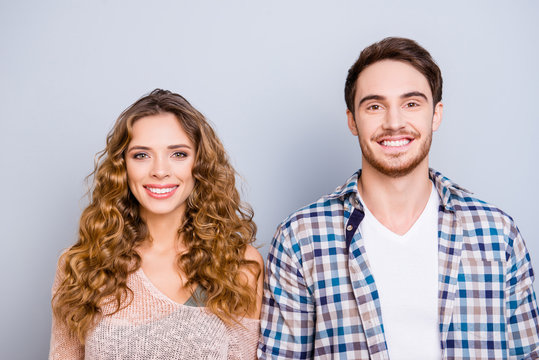 Head shot portrait of cheerful positive couple in casual outfits looking at camera isolated on grey background