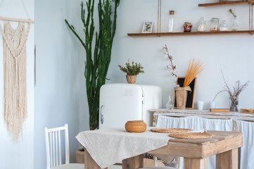 White textured kitchen in the style of shabby. A large textured table in the ecological style and Loft style. Rustic wicker napkins, light green tablecloth, diy.