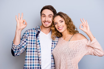 Portrait of lovely cute couple with beaming smiles gesturing ok symbols with fingers looking at...