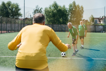 Obraz premium back view of goalkeeper and elderly men on football field