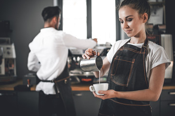 Professional barista woman pouring milk make coffee latte art at cafe