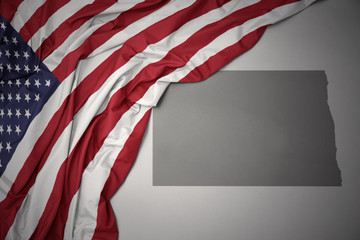 waving national flag of united states of america on a gray north dakota state map background. - obrazy, fototapety, plakaty