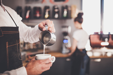 Professional barista pouring milk make coffee latte art