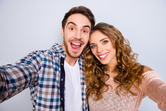 Self portrait of cheerful positive couple keeping mouth open shooting selfie on front camera having online meeting isolated on grey background