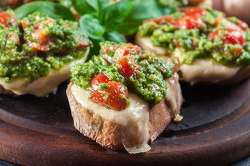 Bruschetta with fresh pesto, mozzarella and cherry tomatoes on cutting board
