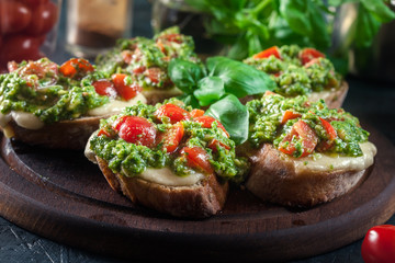 Bruschetta with fresh pesto, mozzarella and cherry tomatoes on cutting board