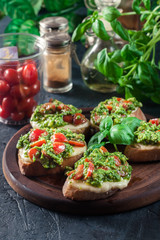 Bruschetta with fresh pesto, mozzarella and cherry tomatoes on cutting board