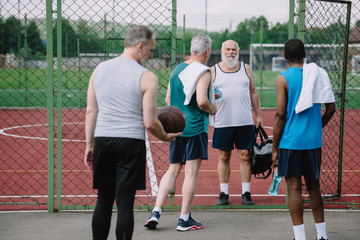group of multiracial old sportsmen with basketball ball on playground