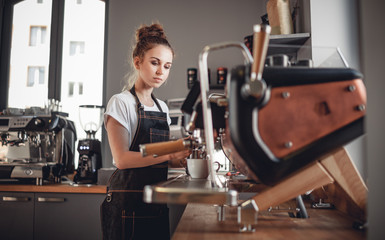 Portrait of professional barista woman in apron making coffee using machine at cafe - obrazy, fototapety, plakaty