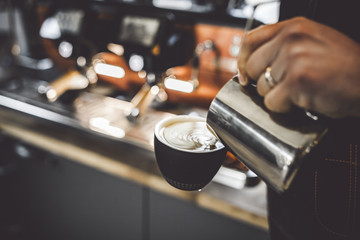 Coffee latte art, barista pouring milk into cup