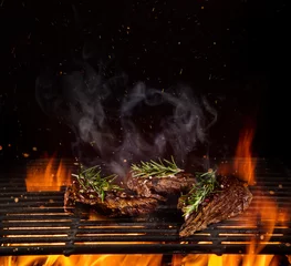 Abwaschbare Fototapete Grill / Barbecue Rindersteaks auf dem Grill mit Flammen