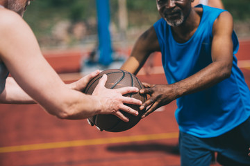 partial view of man giving basketball ball to old african american friend