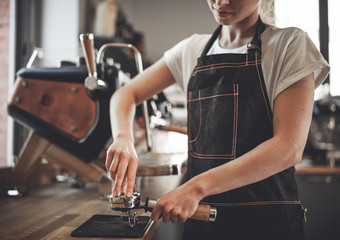 Barista in apron with piston and tamper preparing coffee at cafe