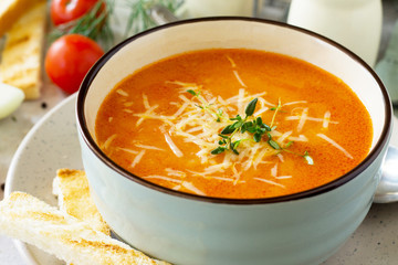 Puree soup tomato with croutons and cheese in a bowl close-up on a light slate background. Diet menu. The concept of healthy eating.