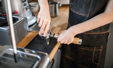 Barista in apron with piston and tamper preparing coffee at cafe