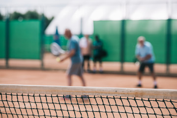 selective focus of net and tennis players playing tennis on court