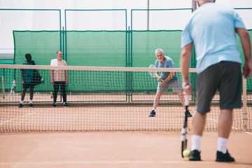 selective focus of old sportsmen playing tennis on court