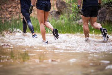 Trail runners moving through water and mud on rural road
