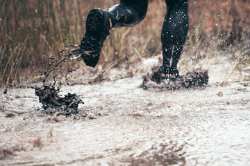 Running through dirty puddle splashing mud, cross country trail