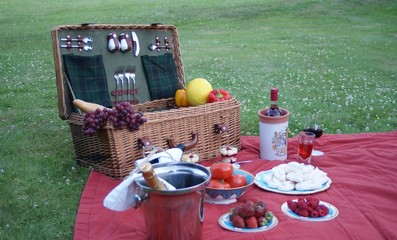 English picnic basket on the picnic blanket with many delicacies and drinks