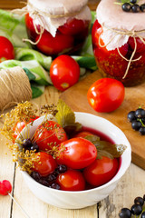 Marinated tomatoes. Pickles tomatoes with black currant on the kitchen table in a rustic style.