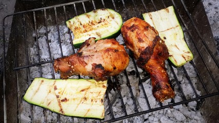 barbecue chicken legs portions and slice zucchini cooked on fire grill. close-up .BBQ