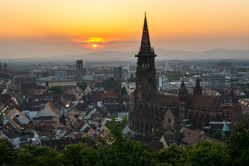 Fototapeta na wymiar Germany, Ancient minster and houses of Freiburg im Breisgau in orange sunset light