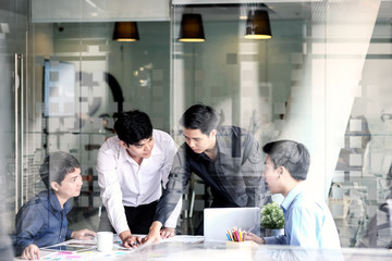 Group of coworkers discussing something on a laptop during a meeting