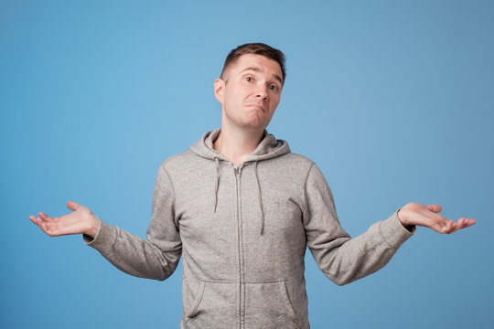 Studio portrait of confused handsome guy showing I have no idea gesture.