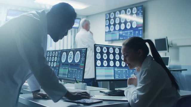 Two Medical Scientists in the Brain Research Laboratory work. Neuroscientists Use Personal Computer with MRI, CT Scans Show Brain Images. Shot on RED EPIC-W 8K Helium Cinema Camera.