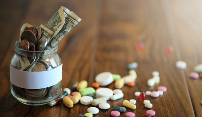 Obraz na płótnie Canvas Drugs and coins in a glass jar on a wooden floor. Pocket savings