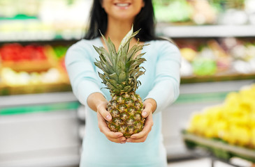 shopping, sale, food, consumerism and people concept - happy woman with pineapple at grocery store