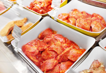 sale and food concept - marinated meat in bowls at grocery stall