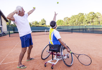 tennis coach teaching a disabled player the service