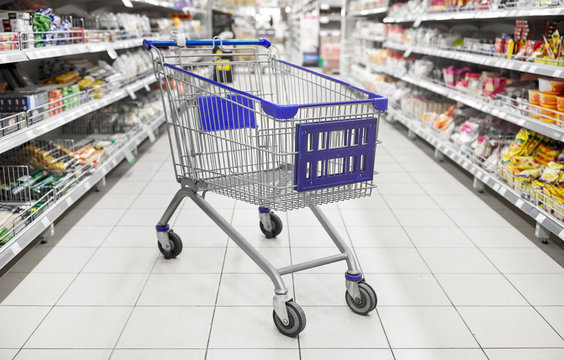 consumerism concept - empty shopping cart or trolley at supermarket