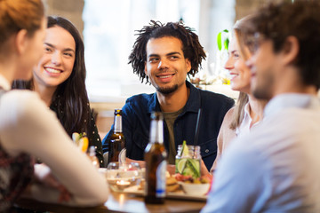 leisure and people concept - happy friends eating and drinking non-alcoholic drinks at bar or restaurant