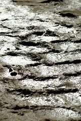 Feucht glänzendes Reifenprofil im regennassen Sand, Nahaufnahme