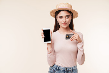 Amazing young pretty woman showing display of mobile phone holding credit card.