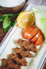 Cigkofte turkish meatball from bulgur with tomato, lemon, and lettuce sides top view