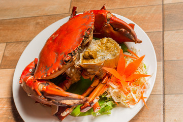 Steamed crab or Boiled crab fresh with crab's spawn in white dish showing the delicious crab's eggs inside its shell on wood table. Thai seafood.