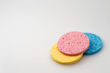 Multicolored bright round cosmetic sponges on a light background with copy space.