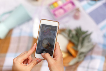 Hands with mobile phone shooting food