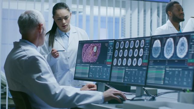 Two Medical Scientists in the Brain Research Laboratory Discussing Progress on the Neurophysiology Project Fighting Tumors. Neuroscientists Use Personal Computer with MRI, CT Scans Show Brain Images. 