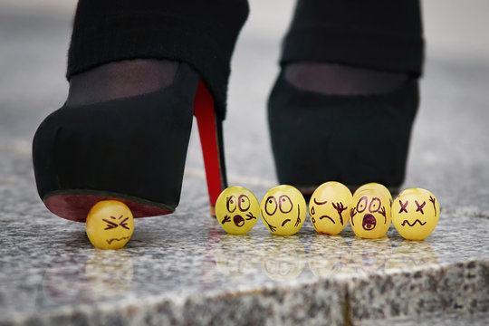 Group of grapes symbolizing the team against the background of high-heeled legs. Crush fetish. Teamwork Problems. Angry boss punish employee.