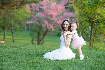 Mom and daughter are two years old sitting on the grass