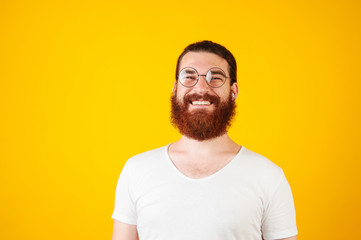 Happy pleased young bearded man wearing white shirt  and round framed glasses. Happiness and Optics concept.