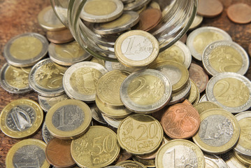 Spilled euro coins from the glass on the wood