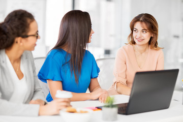 business, teamwork and people concept - female team or businesswomen with laptop computer working at office